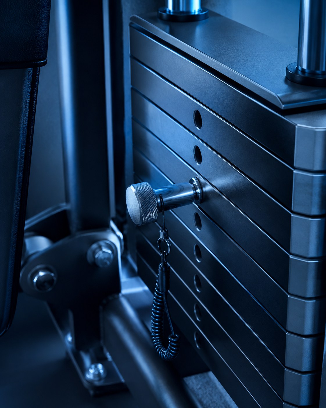 Close-up of the pin-loaded weight stack mechanism on a cable glute kickback machine