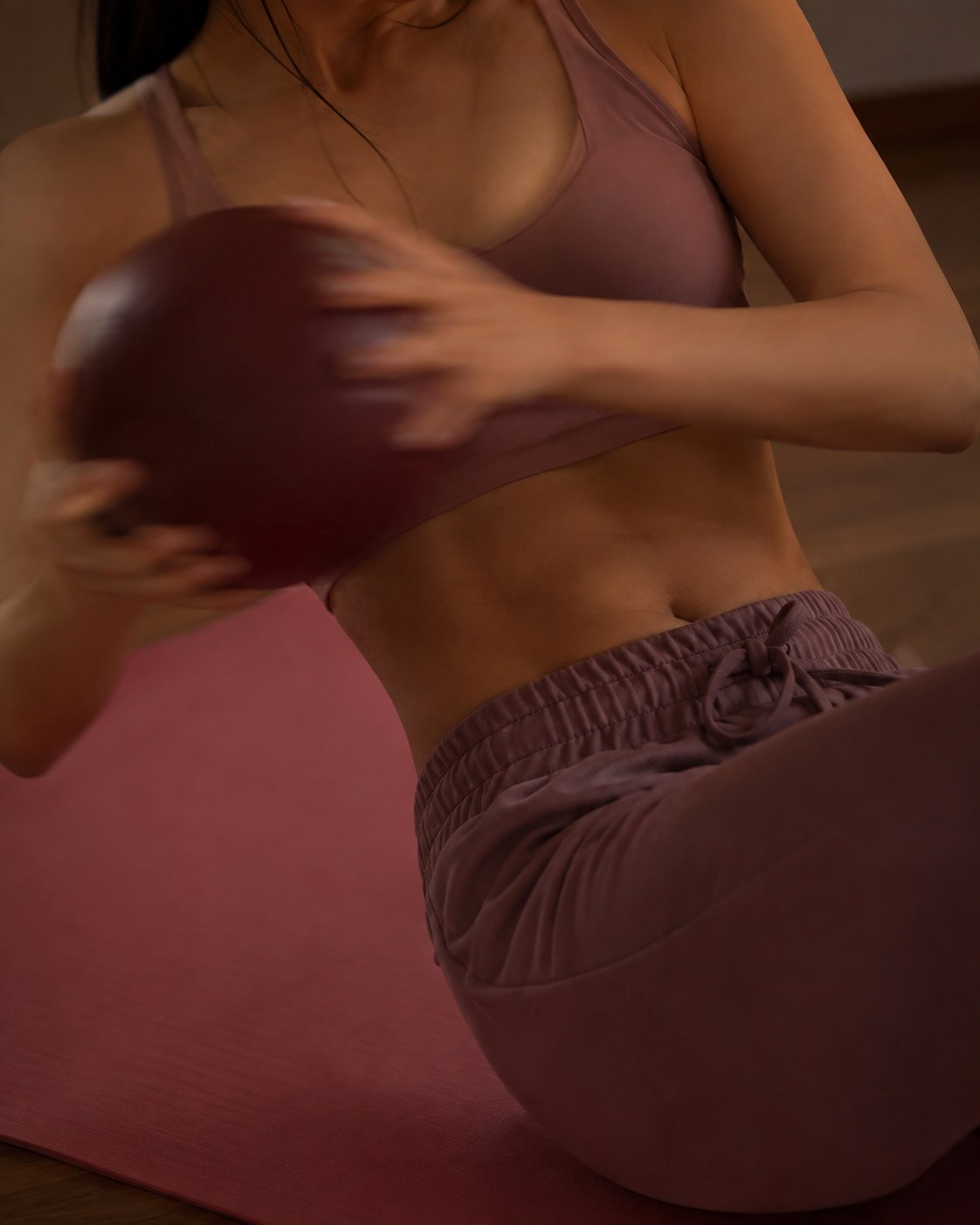 Seated weighted twist using a medicine ball to progress an hourglass workout at home